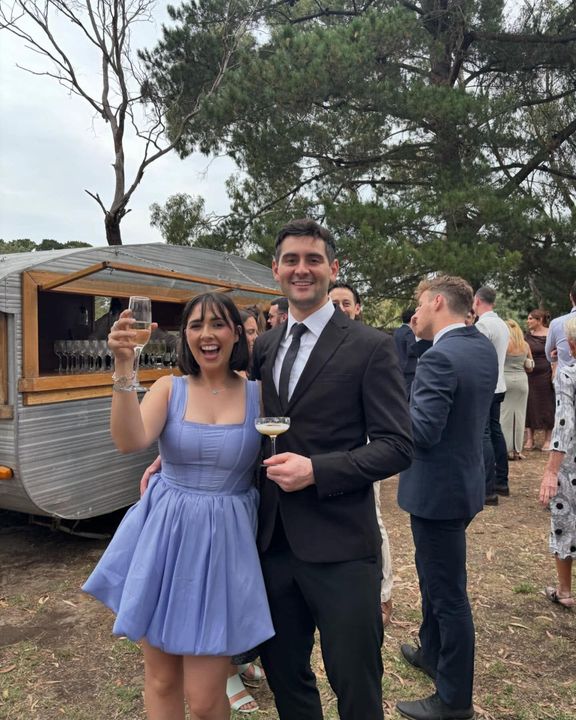 Phoebe and Hayden cheering with drinks at a wedding
